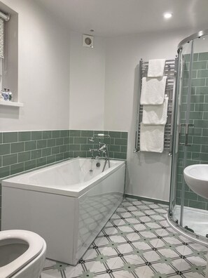 A bathroom with a bathtub, toilet, and shower area.