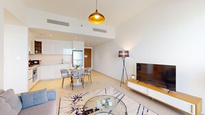 Un salon moderne comprenant un canapé, une table basse, un téléviseur et un coin repas avec des chaises et une table.