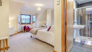 Ein Schlafzimmer mit Bett, Schreibtisch, Stuhl, Fenster und einem Badezimmer mit Dusche.
