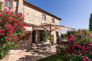A stone building with a patio area featuring outdoor furniture and a large umbrella.