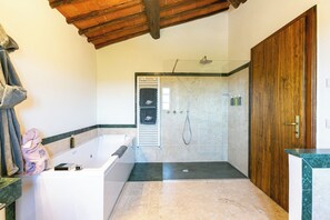 A bathroom with a bathtub, shower, and a wooden door.