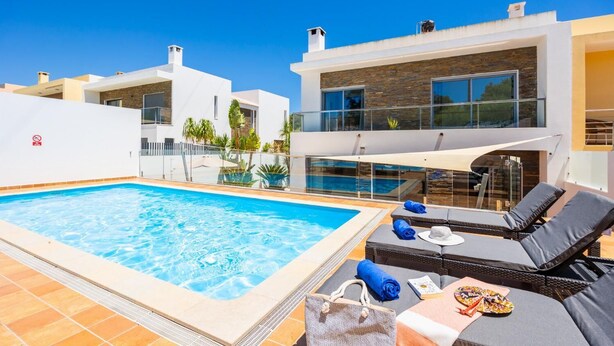 A rooftop pool area with lounge chairs and a modern building in the background. - Villa Clara do Sol - Four Bedroom Villa, Sleeps 8 (Estoi)