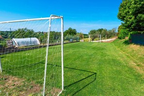 Un campo de fútbol con un arco, rodeado de una valla y vegetación.