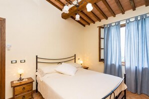 Une chambre à coucher avec un lit, des lampes de chevet, une table de chevet en bois et une fenêtre avec des rideaux.