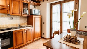A kitchen with wooden cabinets, a microwave, a stove, and a dining table with a vase of flowers.