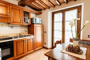 Una cocina con armarios de madera, microondas, estufa y una mesa de comedor con un florero.