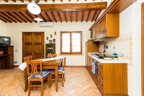 Una cocina con armarios de madera, una mesa de comedor con sillas y un ventanal.