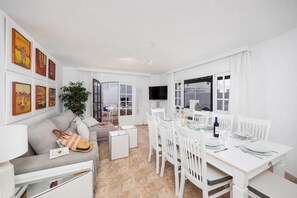 A modern living room with a sofa, coffee table, and dining area with chairs and a table set for a meal.