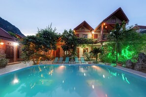 A pool area with lounge chairs and a building with a balcony. - Trang An Family Homestay (Hoa Lu)