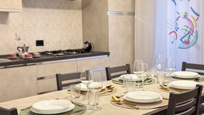 Une table à manger dressée avec des assiettes, des verres et des couverts, avec une cuisine en arrière-plan.