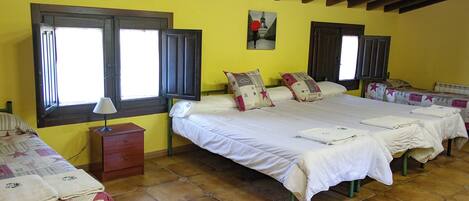 A room with two beds, a nightstand, and a window with shutters.