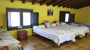 A room with two beds, a nightstand, and a window with shutters.