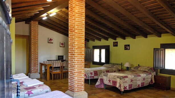 A room with two beds, a desk, and a chair. There are brick pillars and wooden beams on the ceiling.