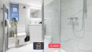 Un baño moderno con cabina de ducha de vidrio, inodoro y lavamanos.