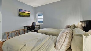 A bedroom with two beds, a desk, and a chair.