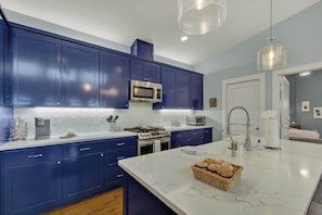 Une cuisine moderne avec des meubles bleu foncé, des plans de travail blancs et un îlot central en marbre.