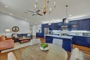 A modern kitchen with dark blue cabinets, a central island, and stainless steel appliances.