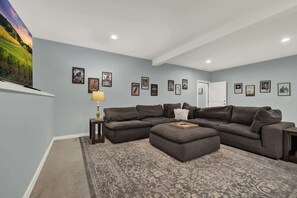 A living room with a sectional sofa, a patterned rug, and framed artwork on the walls.