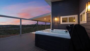 Un jacuzzi en una terraza de madera con vista al paisaje.