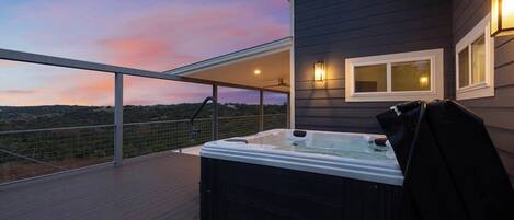 A hot tub on a wooden deck with a view of the landscape.