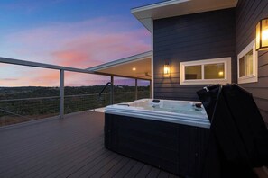 Un jacuzzi en una terraza de madera con vista al paisaje.