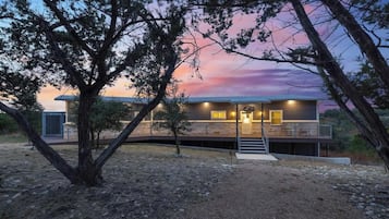 Une maison moderne dotée d’une terrasse couverte et d’un escalier menant à l’entrée.