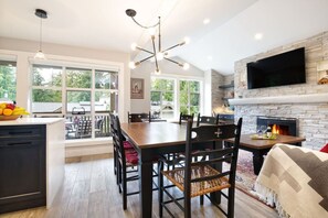 Enjoy family meals and cozy nights by the fireplace in this spacious living area with a large TV and dining table.