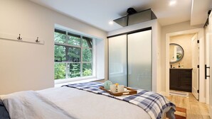 A bedroom with a bed, a window, a sliding door, and a small bathroom visible through the door.