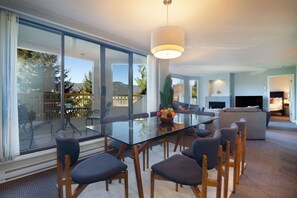 Una sala de estar moderna con una mesa de comedor de vidrio, asientos cómodos y vistas al exterior.