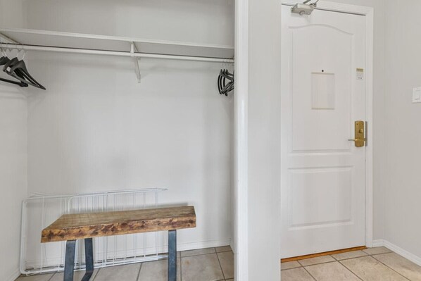 A room with a white door, a wooden bench, and a metal shelf unit. - Prime Ski-in/out 2BR - Pool, HT, Sauna, EV Charger (Whistler)