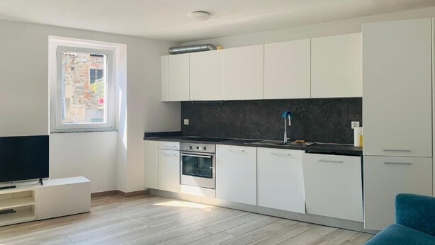 A modern kitchen with white cabinets, a black countertop, and a built-in oven. - 2Curio Court House Charming Lodge (Curio)
