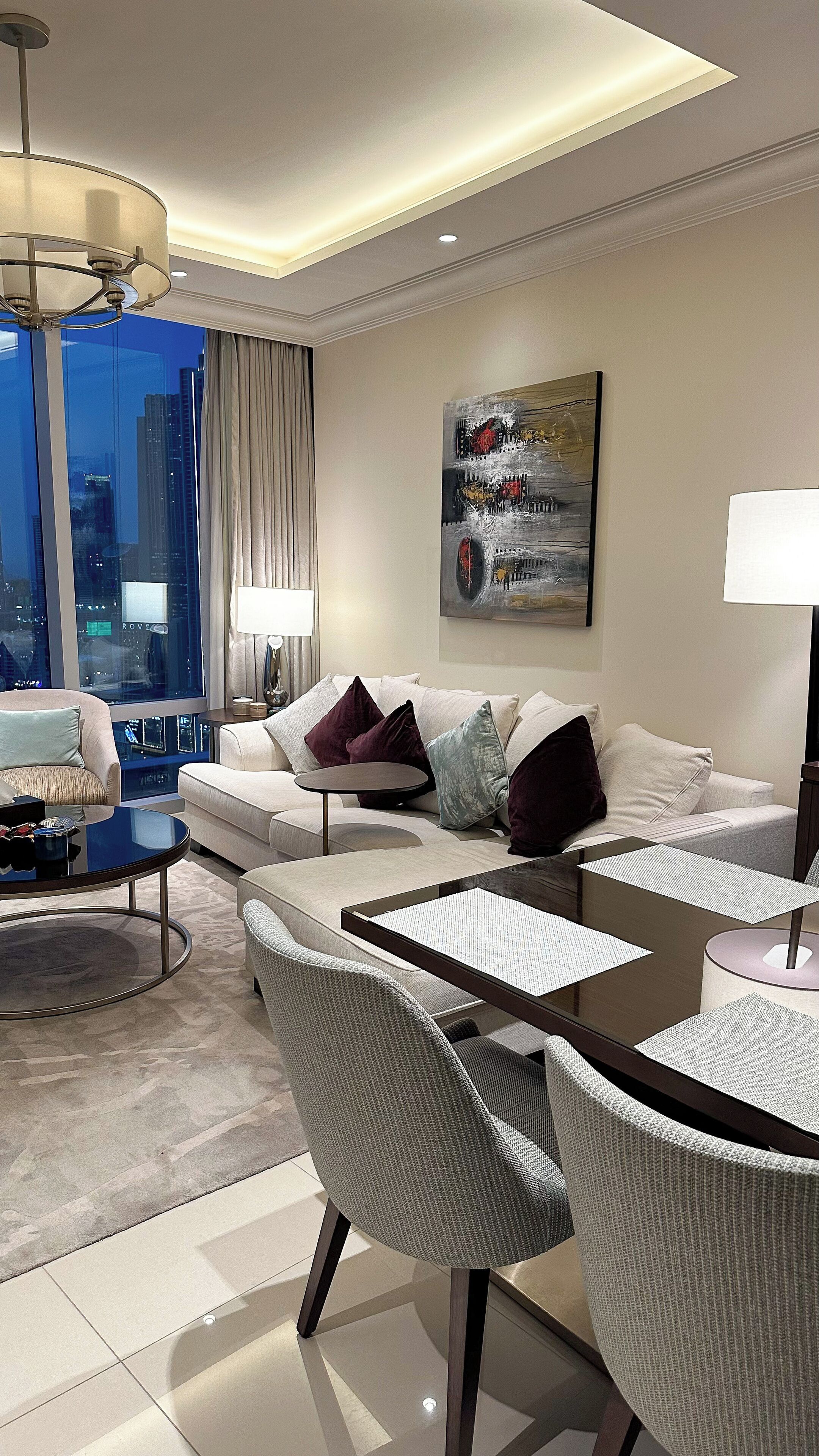 A modern living room with a sofa, chairs, a coffee table, and a painting on the wall.