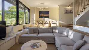 A modern living room with a large sectional sofa, a dining table with chairs, and a staircase. - Agras 41·Spacious 4bdr Townhouse with Monumental V (Athens)