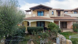 Una casa de dos pisos con techo de tejas, balcón y un porche cubierto.