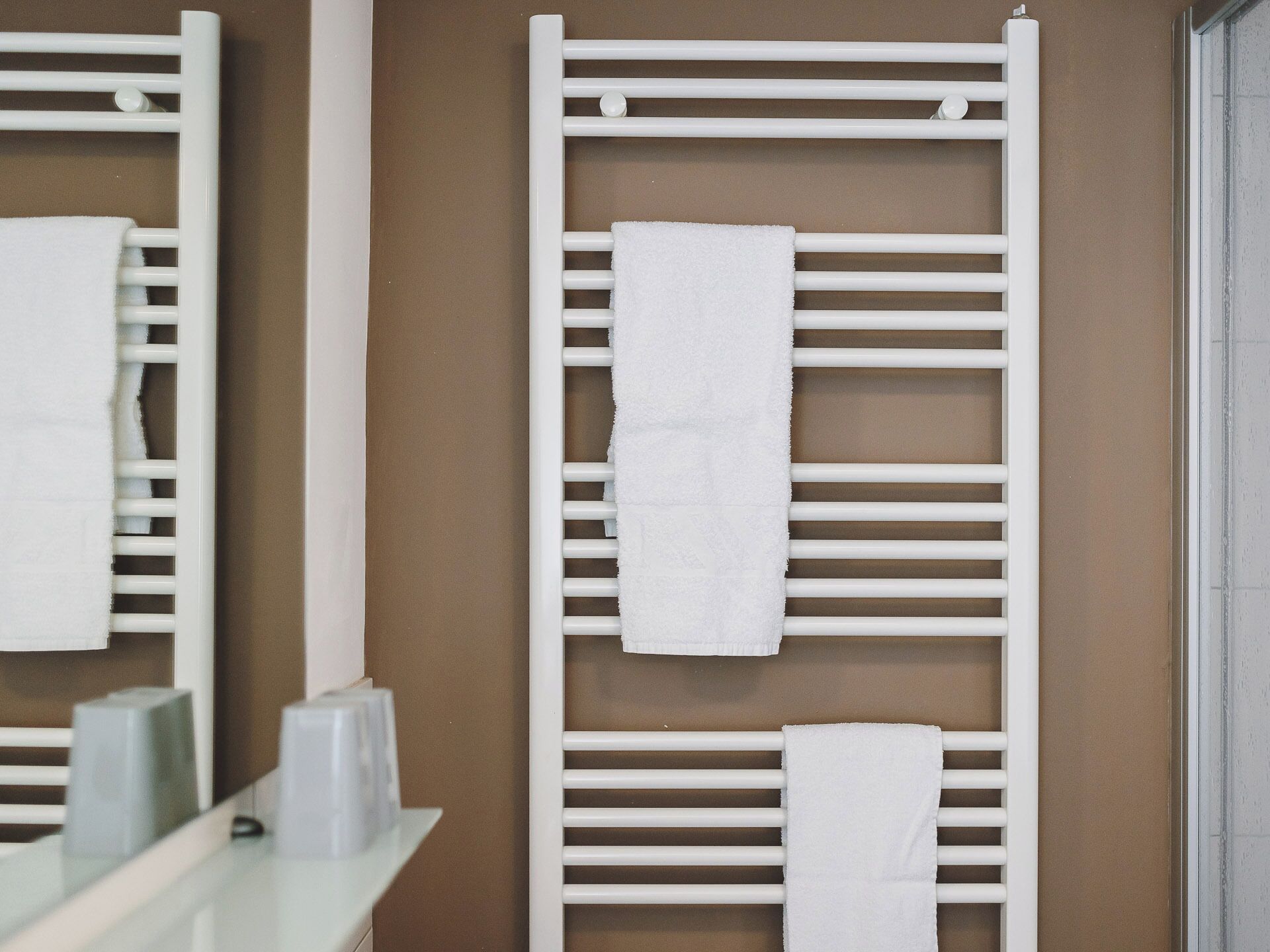 A bathroom with a white towel rack, a mirror, and a brown wall.