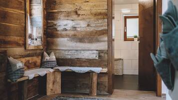 Cozy interior space with a bench against a wooden wall, a woven rug, and a door leading to another room.