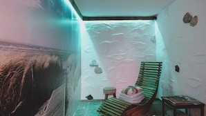 A room with a sloped ceiling, a wooden bench, a small stool, and a wall with rocks. - Chalet Naila by we rent (Bruck an der Grossglocknerstrasse)