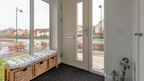 A room with a bench, wicker baskets, and a view of the street through large windows. - Belmont House | Kingsbarns (Kingsbarns)