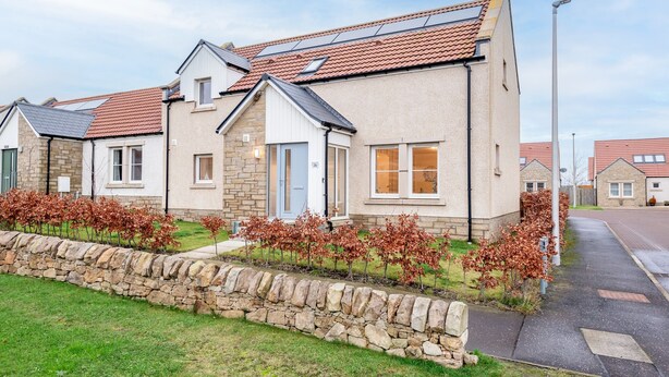 A row of modern houses with stone foundations, red-tiled roofs, and solar panels. - Belmont House | Kingsbarns (Kingsbarns)
