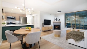 A modern kitchen with a dining area, a fireplace, and a large window with a view. - True Luxury - Pool, HT, Sauna (Whistler)