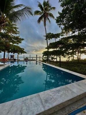 Relax by the serene pool surrounded by lush greenery and a stunning sea view.