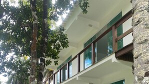 A two-story building with a balcony, large windows, and a stone pillar. - Pousada Conchas Do Mar (Cairu)