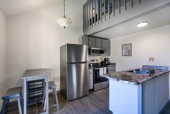 A modern kitchen with stainless steel appliances, a built-in microwave, and a granite countertop island with a sink.