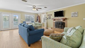A living room with a blue sofa, a green sofa, a fireplace, and a TV mounted on the wall.
