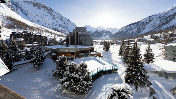 A snow-covered mountain resort with modern buildings, a ski lift, and a clear view of the surrounding mountains. - Beautiful renovated apartment (Val-d'Isère)