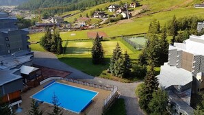 A resort with a swimming pool, a tennis court, and a mountainous backdrop. - Beautiful renovated apartment (Val-d'Isère)