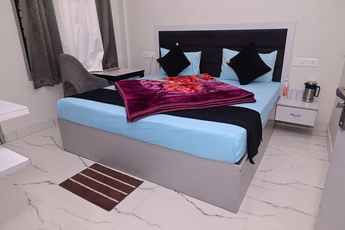 A neatly arranged hotel room with a bed, bedside table, and a small desk.