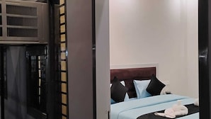 A modern hotel room with a bed, a window, and an air conditioning unit. - Aastha Guest House (Roorkee)