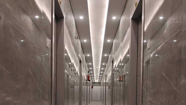 A long, narrow hallway with reflective marble floors and walls, lined with doors and illuminated by overhead lights. - Aastha Guest House (Roorkee)