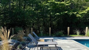 A poolside area with two lounge chairs and a concrete deck.